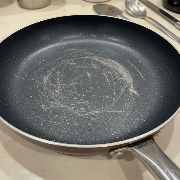 Emeril Lagasse Forever Pan showing signs of wear and scratches on its non-stick coating after extended use.